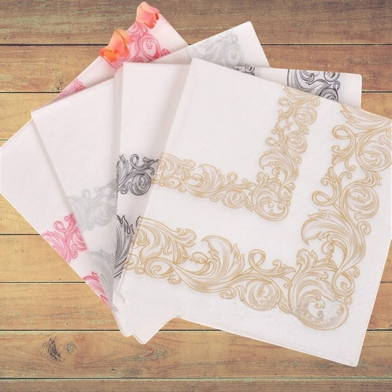 CrossWave Ecopacks white paper napkins with ornate gold, pink, and grey floral border designs, 23x23cm.